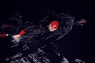 Image showing triathlon athlete swimming in dark night wearing wetsuit