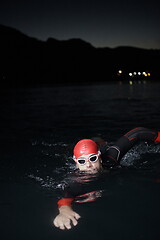 Image showing triathlon athlete swimming in dark night wearing wetsuit