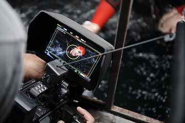 Image showing videographer taking action shot of triathlon swimming athlete at night