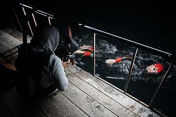 Image showing videographer taking action shot of triathlon swimming athlete at night