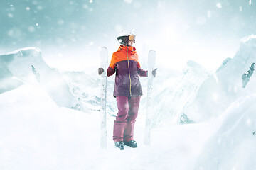 Image showing Female skier standing with skies in one hand on background mountain landscape