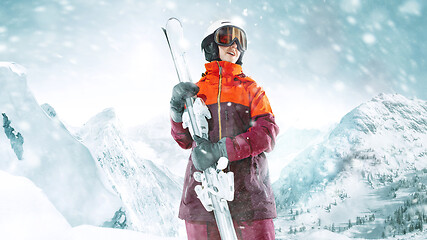 Image showing Female skier standing with skies in one hand on background mountain landscape