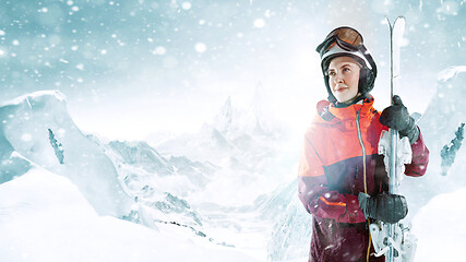 Image showing Female skier standing with skies in one hand on background mountain landscape