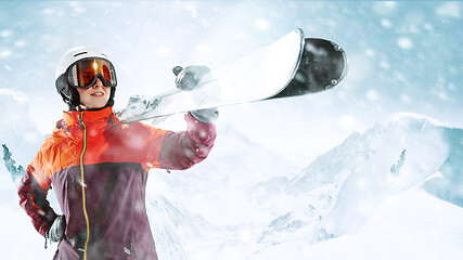 Image showing Female skier standing with skies in one hand on background mountain landscape