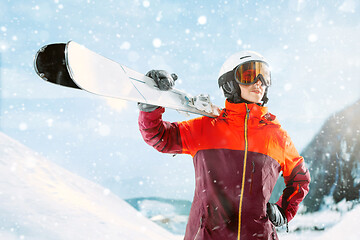 Image showing Female skier standing with skies in one hand on background mountain landscape