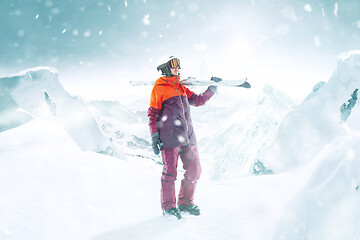 Image showing Female skier standing with skies in one hand on background mountain landscape