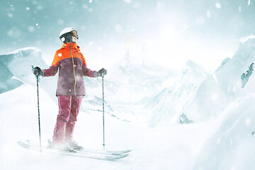 Image showing Female skier standing with skies in one hand on background mountain landscape