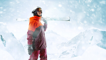 Image showing Female skier standing with skies in one hand on background mountain landscape