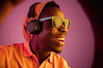 Image showing The young handsome hipster man listening music with headphones