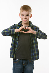 Image showing A boy of ten years shows a heart with two hands on his chest