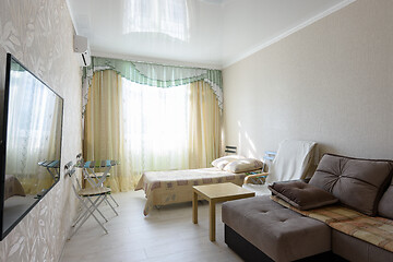 Image showing Spacious bedroom interior with large sofa and bed, and glossy stretch ceiling