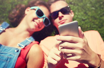 Image showing teenage couple with smartphone lying on grass
