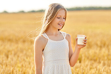 Image showing happy girl with glass of milk on cereal field