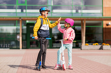 Image showing school kids riding scooters and making high five