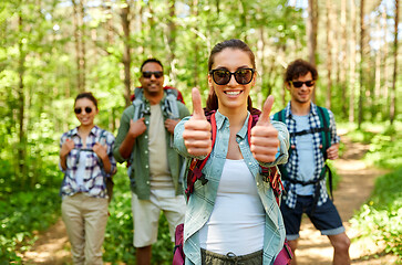 Image showing friends with backpacks showing thumbs up in forest