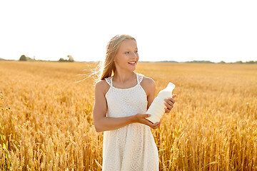 Image showing happy girl with bottle of milk on cereal field