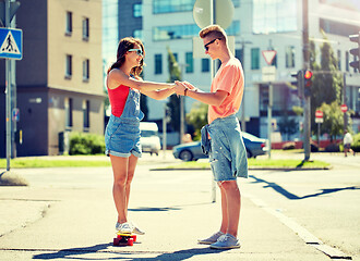 Image showing teenage couple riding skateboards on city street