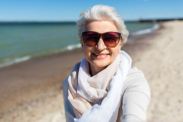 Image showing senior woman in sunglasses taking selfie on beach