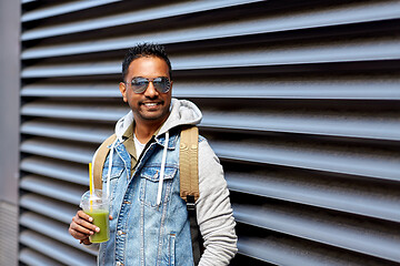 Image showing man with backpack drinking smoothie on street