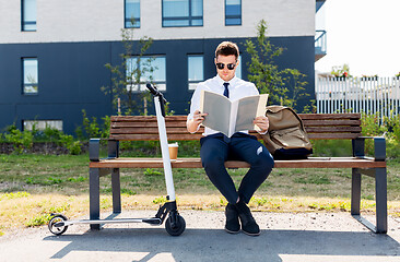Image showing businessman with file and scooter sitting on bench