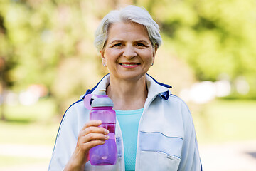 Image showing sporty senior woman with bottle of water at park