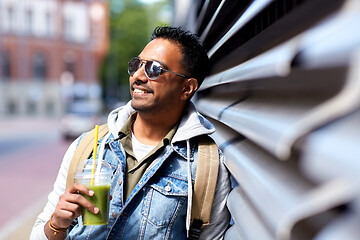 Image showing man with backpack drinking smoothie on street