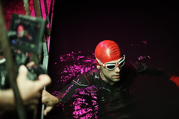 Image showing videographer taking action shot of triathlon swimming athlete at night