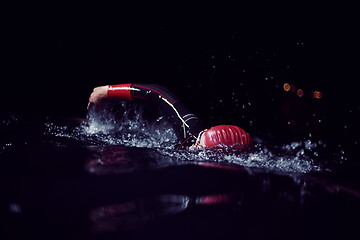 Image showing triathlon athlete swimming in dark night wearing wetsuit