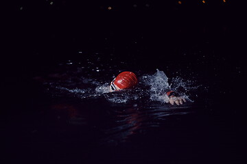 Image showing triathlon athlete swimming in dark night wearing wetsuit