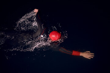 Image showing triathlon athlete swimming in dark night wearing wetsuit