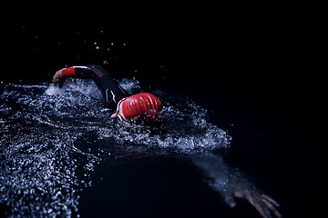 Image showing triathlon athlete swimming in dark night wearing wetsuit