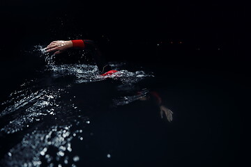 Image showing triathlon athlete swimming in dark night wearing wetsuit