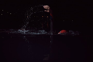 Image showing triathlon athlete swimming in dark night wearing wetsuit