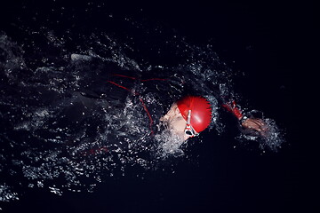 Image showing triathlon athlete swimming in dark night wearing wetsuit