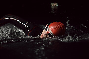 Image showing triathlon athlete swimming in dark night wearing wetsuit