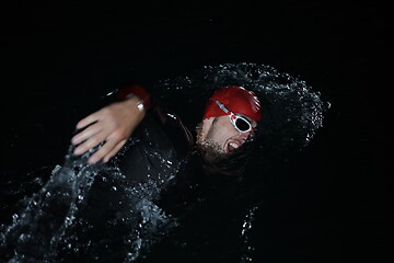 Image showing triathlon athlete swimming in dark night wearing wetsuit