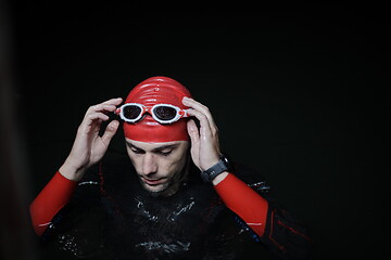 Image showing authentic triathlete swimmer having a break during hard training on night