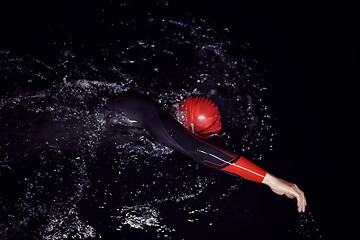 Image showing triathlon athlete swimming in dark night wearing wetsuit