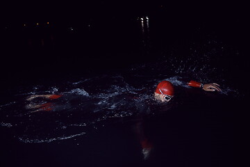 Image showing triathlon athlete swimming in dark night wearing wetsuit