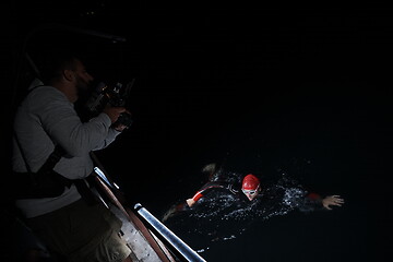 Image showing videographer taking action shot of triathlon swimming athlete at night