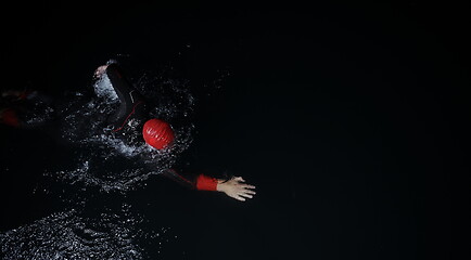 Image showing triathlon athlete swimming in dark night wearing wetsuit