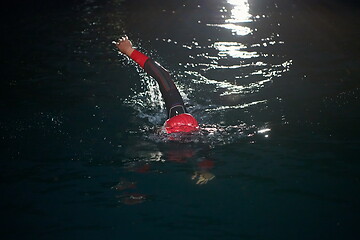 Image showing triathlon athlete swimming in dark night wearing wetsuit