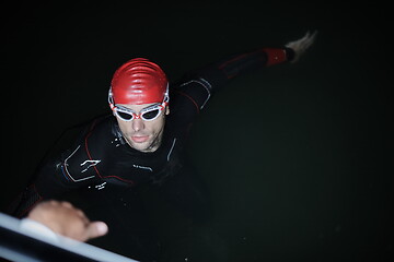 Image showing authentic triathlete swimmer having a break during hard training on night