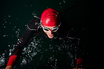 Image showing triathlon athlete swimming in dark night wearing wetsuit