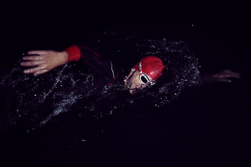 Image showing triathlon athlete swimming in dark night wearing wetsuit