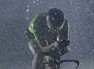 Image showing triathlon athlete riding bike on rainy night