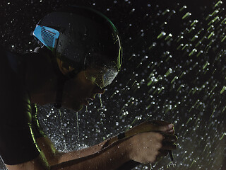 Image showing triathlon athlete riding bike on rainy night