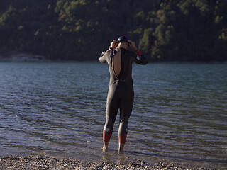 Image showing authentic triathlon athlete getting ready for swimming training on lake