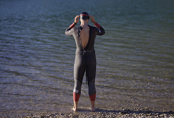 Image showing authentic triathlon athlete getting ready for swimming training on lake