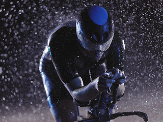 Image showing triathlon athlete riding bike on rainy night